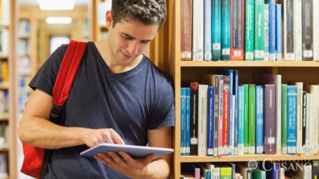 studente universitario verifica equiparazione lauree su un tablet dentro una biblioteca